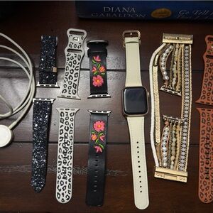 Apple Watch with Beige Band and Assorted Black, White, Gold, and Brown Straps